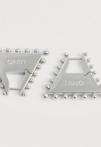 Ασημένια τριγωνικά σκουλαρίκια με μικρές ασημένιες μπάλες κατά μήκος των άκρων, ένα από τα οποία φέρει την εγγραφή "LIU JO", σε λευκό φόντο.