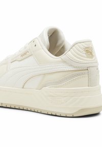 Krém színű sneaker, bőr felsőrésszel és texturált részletekkel. Vastag talppal, azonos színű díszítésekkel és Puma logóval a saroknál és az oldalon.