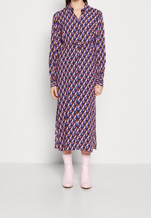Langärmliges, knopfbares Kleid mit einem Rautenmuster in Lila, Rosa und Blau. Verfügt über eine gebundene Taille und wird mit rosa Absatzstiefeln kombiniert.
