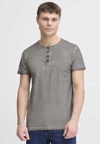 Grå kortermet henley-t-skjorte laget av mykt stoff, med rund hals, fire knapper foran og oppbrettede ermer.