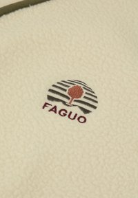 Tessuto in pile crema con un logo circolare ricamato con strisce, un design di albero in marrone e il testo "FAGUO" in bordeaux.