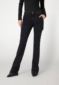 Jean cargo noir avec une coupe droite. Comprend deux poches latérales, des détails de surpiqûres subtils, et une taille mi-haute.