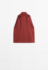 Blouse en lin rouge rouille sans manches, à col haut, avec fentes ouvertes aux bras, étalée à plat sur un fond blanc.