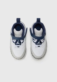 Weiße und graue Sneaker mit strukturierter Oberfläche, navyblauen Akzenten, verstellbarem Riemen und schwarzer gummierter Sohle mit Muster.