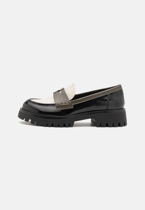 Sort og hvid chunky loafer med tyk rillede sål, glat læderoverdel og flettet remdetalje over toppen.