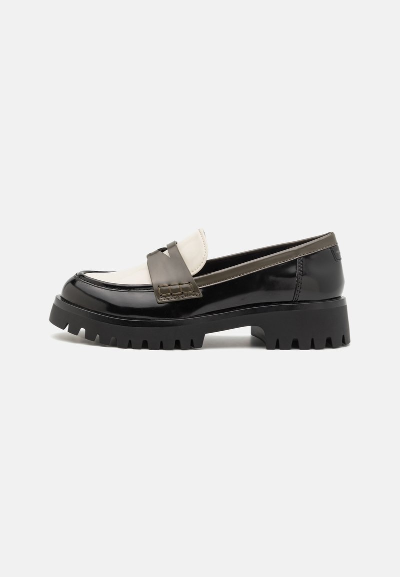 Mocassin chunky noir et blanc avec semelle épaisse à rainures, tige en cuir lisse, et détail de bride tressée sur le dessus.