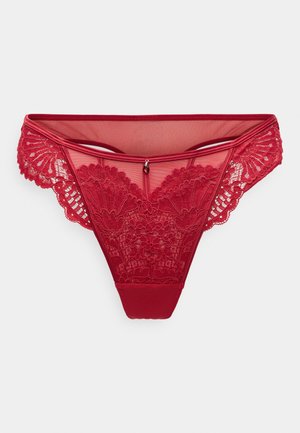 String en dentelle rouge avec des panneaux en maille translucide, des détails de broderie florale et un petit accent en métal décoratif au centre devant.