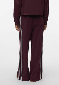 Bordånga sweatpants med vida ben, som har två vertikala vita ränder på varje sida. Tillverkade av mjukt material med en avslappnad passform.