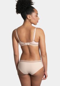 Ensemble de soutien-gorge et culotte nude avec des bretelles réglables, texture lisse et délicat détail de dentelle le long de la taille.