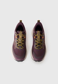 Purple athletic shoes with mesh upper, textured tan sole, green laces, and orange accent. Features logo on the side and pull tab at heel.