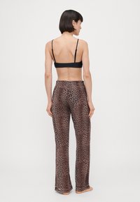 Black bralette paired with loose-fitting, leopard-print pants in shades of brown, featuring an elastic waistband and soft fabric texture.