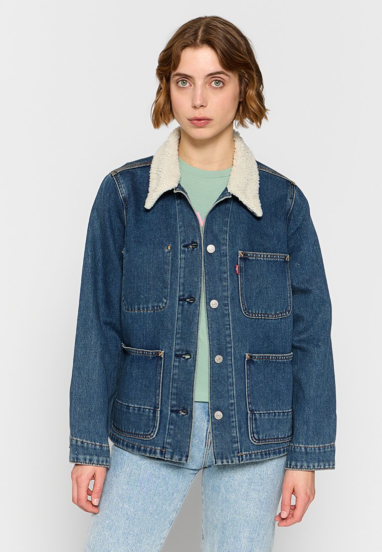 Chaqueta de denim en azul oscuro con un collar de borreguillo color crema. Presenta cierres de botones, cuatro bolsillos frontales y un ajuste relajado. Tela texturizada.