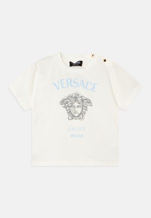 T-shirt de algodão branco com texto "VERSACE" em azul claro e uma imagem da Medusa em cinza. Dois botões dourados no ombro acrescentam um detalhe único.