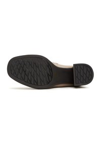 Semelle d'une chaussure beige avec des parties en caoutchouc noir au talon et à l'avant-pied présentant des motifs diagonaux pour l'adhérence.