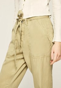 Pantaloni khaki realizzati in tessuto morbido, con un laccetto in vita, ampie tasche laterali e una vestibilità rilassata con dettagli di cucitura discreti.