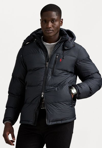Dunkelblaue Pufferjacke mit Kapuze, durchgehendem Reißverschluss und rotem Logo-Akzent. Strukturierter Stoff mit ge quiltetem Design und zwei Seitentaschen.