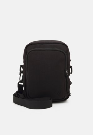 Zwarte stoffen crossbodytas met een voorvak met rits, verstelbare band en een gladde textuur. Heeft een minimalistisch ontwerp zonder zichtbare merken.