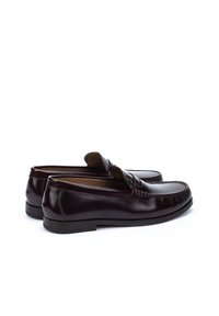 Mocasines de cuero marrón con un acabado suave, punteras redondeadas, costuras suaves y un pequeño acento elevado en el empeine. Suelas de goma para mayor agarre.