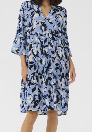 Robe ample atteignant les genoux avec un motif floral abstrait en bleu, noir et blanc, manches évasées trois-quarts et encolure en V.