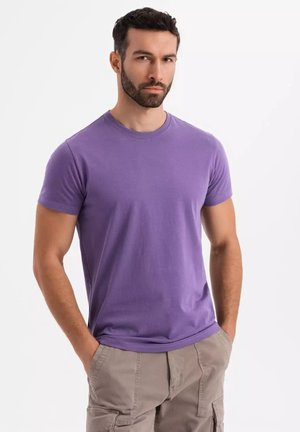 T-shirt di cotone viola con scollatura tonda e maniche corte, caratterizzato da una texture liscia e un design aderente. Indossato con pantaloni cargo beige.