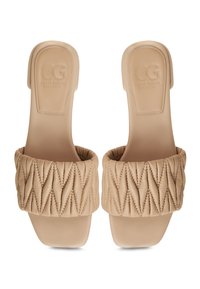 Le ciabatte beige presentano un cinturino imbottito e trapuntato con cuciture a rombi, una suola piatta e un design minimale e liscio. Logo impresso sulla soletta.