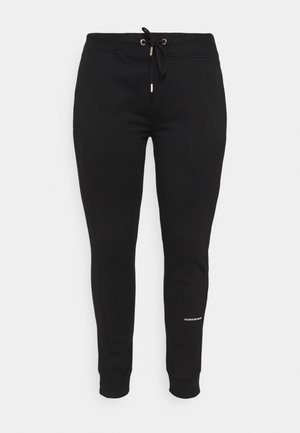 Svarta mjukisbyxor i mjukt tyg med dragsko i midjan, smal passform och ribbade muddarna. Diskret logotypdetalj nära vristen.