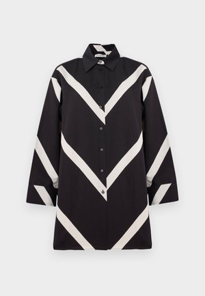 Svart långärmad skjorta med knappar, dekorerad med breda vita chevron-ränder på framsidan, ärmarna och kragen.