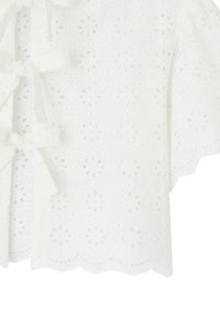 Haut court à manches courtes en coton brodé, doté de découpes florales, d'un ourlet en forme de vagues et de liens aux épaules pour un ajustement réglable.