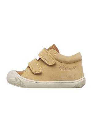 Scarpa per bambino in camoscio beige con due cinturini in velcro, punta arrotondata in gomma bianca e suola strutturata su sfondo bianco.