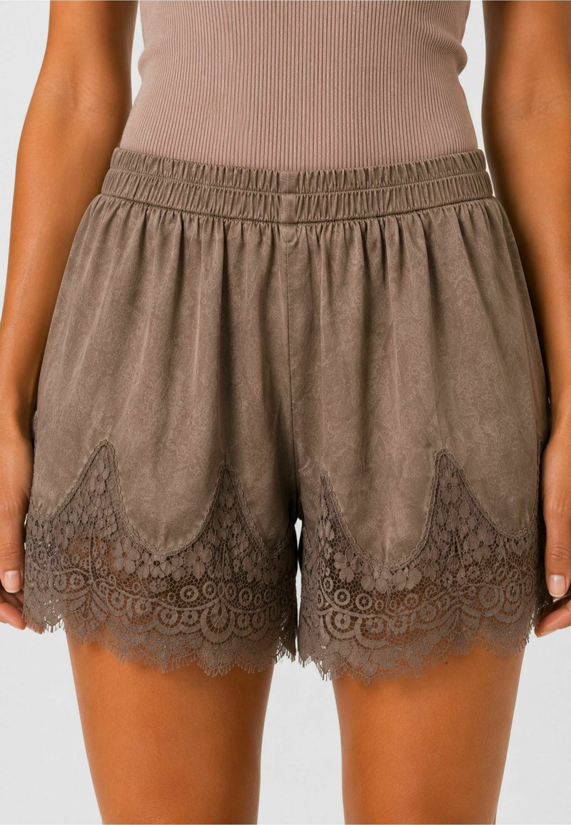 Femme portant un short taille élastique taupe avec une bordure en dentelle florale à l'ourlet et un débardeur côtelé rentré.