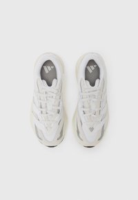 Baskets blanches avec un dessus en mesh, des lacets et trois accents rayés. Superpositions texturées remarquables et une semelle intermédiaire beige avec une semelle extérieure noire.