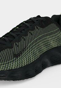 Μαύρο και πράσινο παπούτσι Nike με παχύ υφασμάτινο πάτο, κλείσιμο με κορδόνια και κεντημένο λογότυπο της εταιρείας στο πλάι.