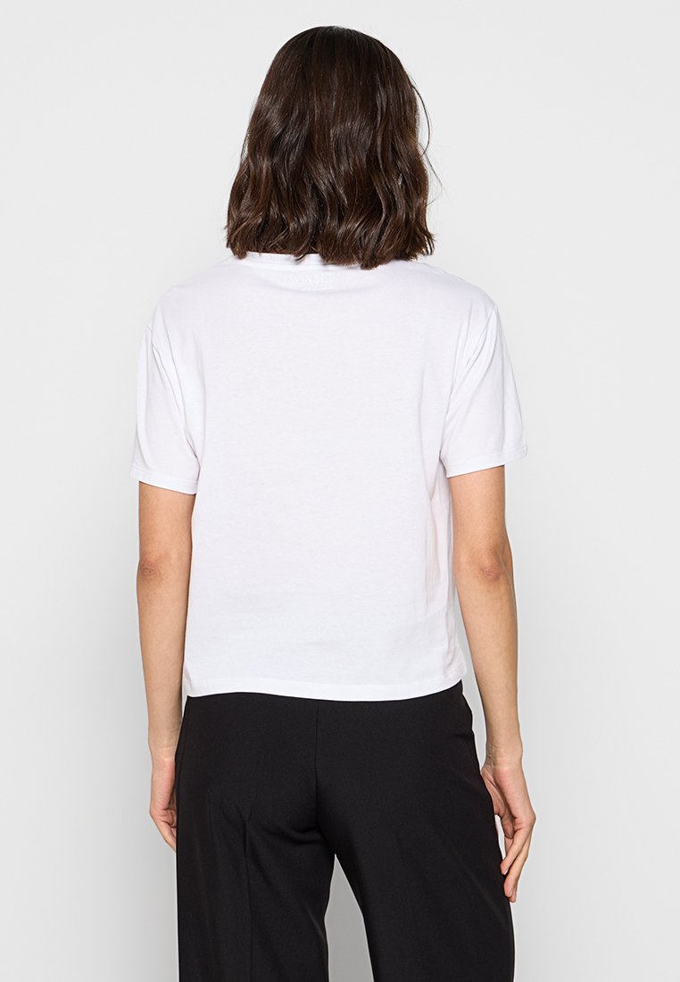Biały skrócony t-shirt wykonany z bawełny, z krótkim rękawem i luźnym krojem, z okrągłym dekoltem. Gładka tekstura bez widocznych wzorów.