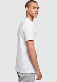 Hvid kortærmet t-shirt i bomuld, med en klassisk rund hals og en afslappet pasform, vist på en mandlig model i profil.
