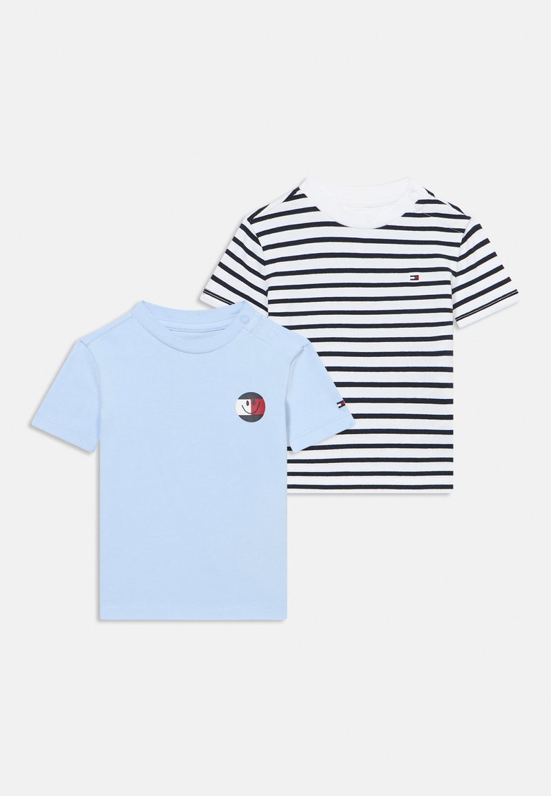 Δύο κοντομάνικα μπλουζάκια: το ένα ανοιχτό μπλε με στρογγυλό λογότυπο, το άλλο λευκό με ναυτικές ρίγες και μικρό λογότυπο στο στήθος.