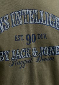 Olivengrøn T-shirt med navyblåt tekstdesign: "INTELLIGENCE EST. 90 DIV. AF JACK & JONES Rugged Denim," med varieret typografi.