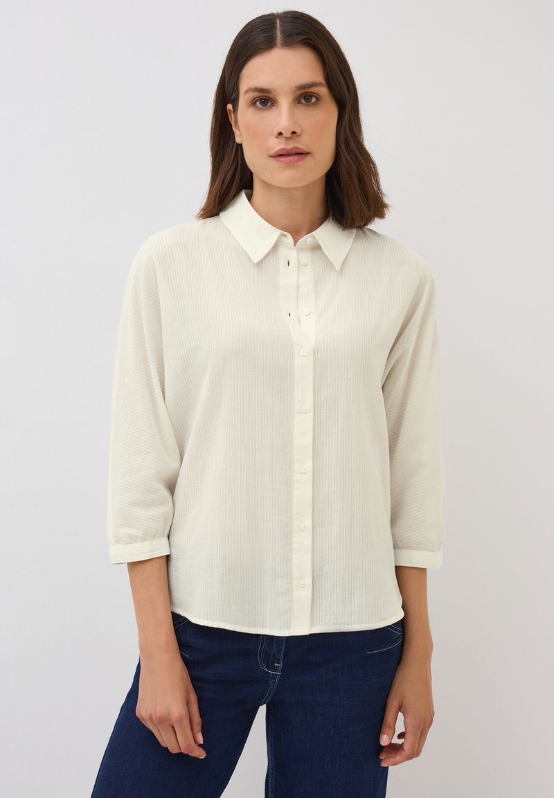 Blusa leggera color crema, con una sottile texture a righe, maniche a tre quarti e colletto. Design con bottone frontale.