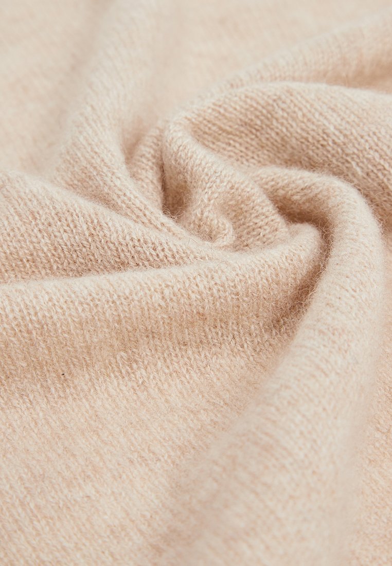 Weiche, leichte Stoff in einem hellen Beige mit einer glatten, leicht flauschigen Textur; verfügt über ein zartes Strickmuster mit subtilen Variationen.