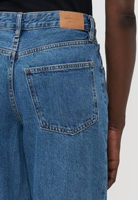 Blå denim jeans med rett snitt, med et skinnmerke i livet og en baklomme med dobbelt stikking rundt kanten.