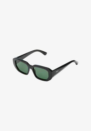 Lunettes de soleil rectangulaires noires avec montures épaisses et verres vert foncé, vue en angle montrant une branche avec le logo Komono.