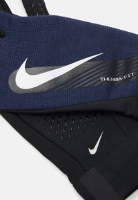 Vêtements Nike Therma-FIT en bleu marine et noir, présentant un tissu texturé, un logo blanc bien visible et des accents en mesh respirant.