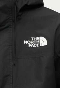 Μαύρο μπουφάν από ελαφρύ ύφασμα, με κουκούλα, μπροστινή τσέπη και ξεχωριστό λευκό κεντητό λογότυπο στο στήθος.