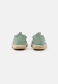 Grønne lerrets espadriller med jute såle, med flat bak og små stoffsløyfer for enkel påkledning. Enkel, allsidig design.