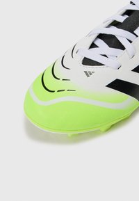 Scarpini da calcio bianchi e verde neon con accenti neri, caratterizzati da una texture liscia, un design curvo e una chiusura con lacci con linee distintive.