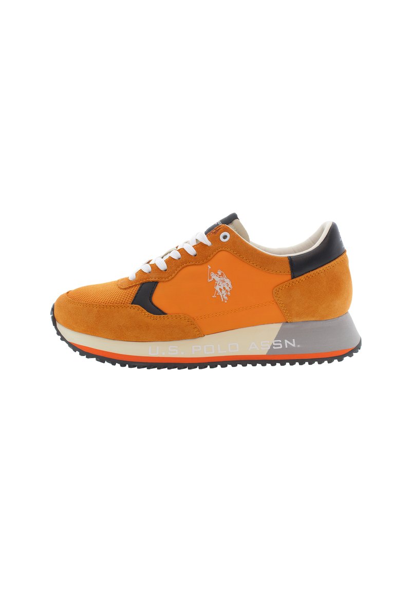 Orange athletic shoe featuring a mix of suede and textile materials, white laces, black accents, and a grey sole with branding.