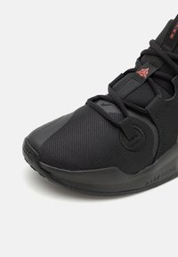 Czarny but sportowy wykonany z materiałów tekstylnych i syntetycznych; posiada teksturowaną cholewkę, sznurowanie oraz widoczną podeszwę amortyzującą.