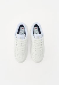 Baskets blanches en cuir lisse avec un bout perforé, design à lacets, col rembourré et doublure en tissu avec une étiquette à l'intérieur.