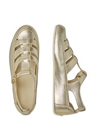 Bottes dorées en métal à bout fermé avec un design de sangle entrecroisée et des côtés ouverts, dotées d'une semelle intérieure rembourrée et d'une semelle blanche flexible.