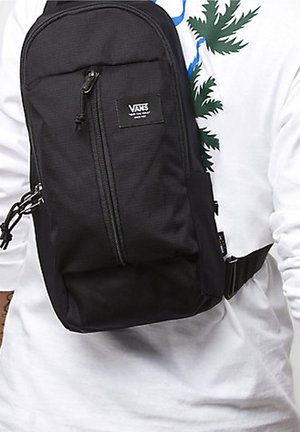 Borsa a tracolla nera Vans con tasca frontale con zip, tracolla regolabile e materiale texturizzato. Caratterizzata da un patch con il logo nella parte anteriore.