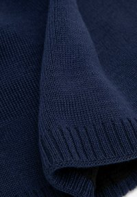 Granatowa dzianina o gładkiej fakturze i prążkowanych krawędziach, ukazująca zbliżenie splotu i miękkości.